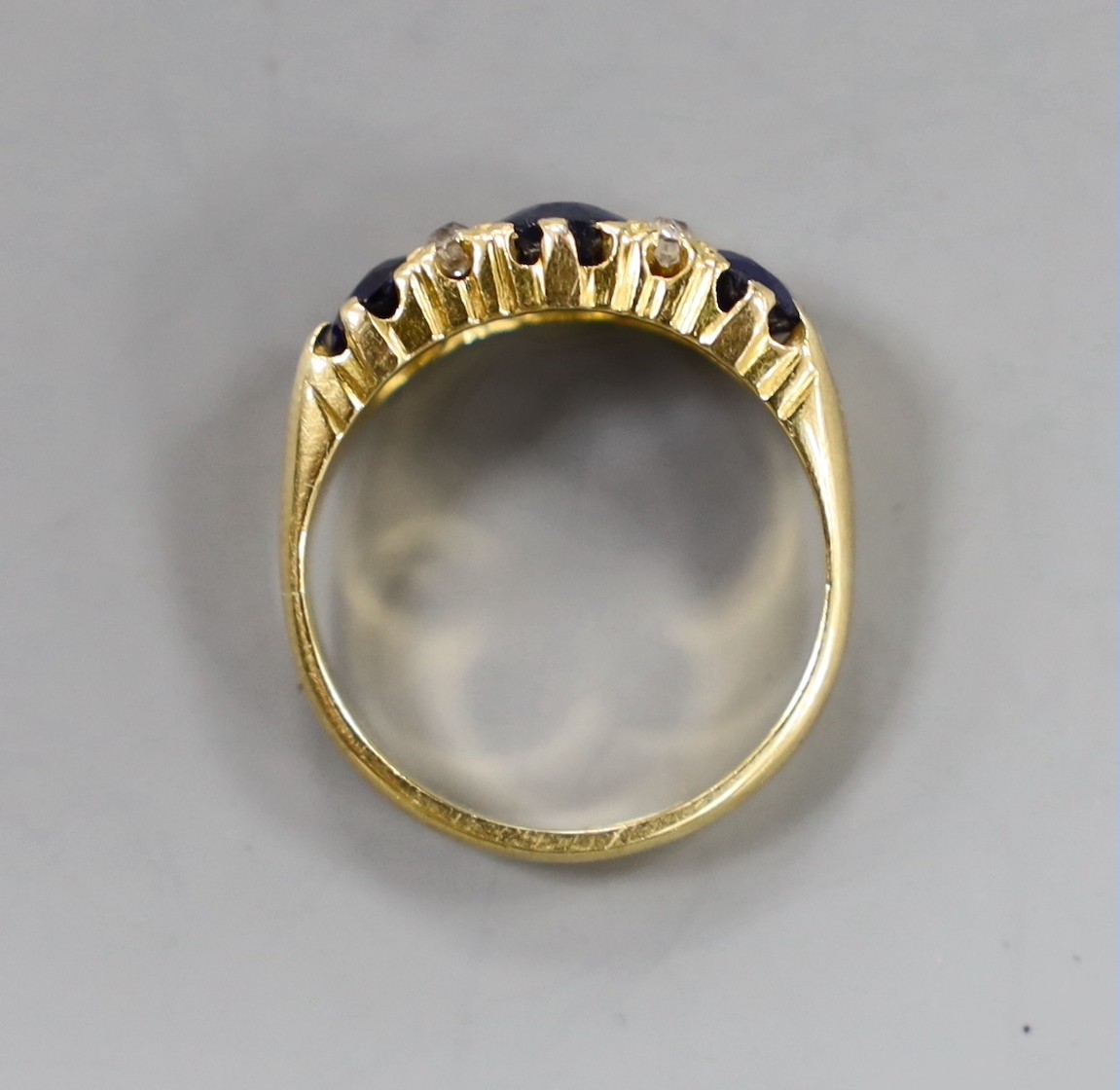 An 18ct, three stone sapphire and four stone diamond chip set half hoop ring, size L, gross weight 4 grams.